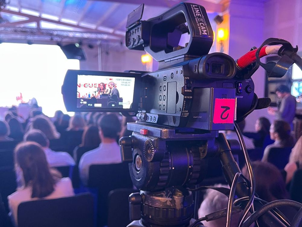 Cámara grabando una mesa redonda durante un congreso con público en sala