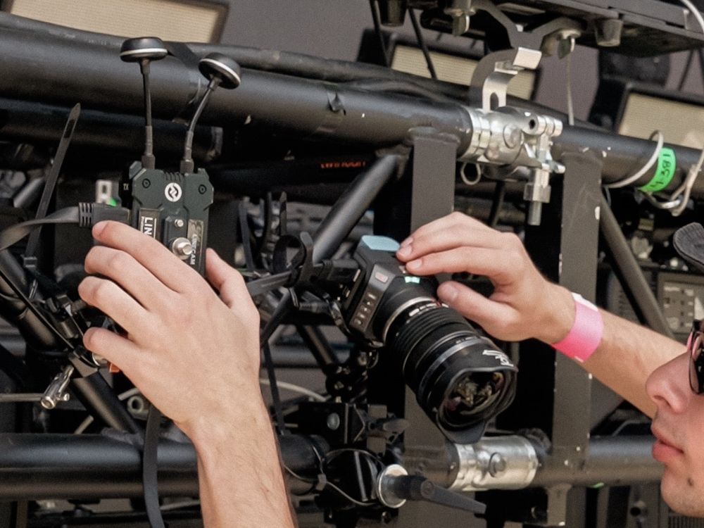 Técnico instalando una cámara compacta de estudio 4K con transmisor inalámbrico Hollyland en el truss del escenario