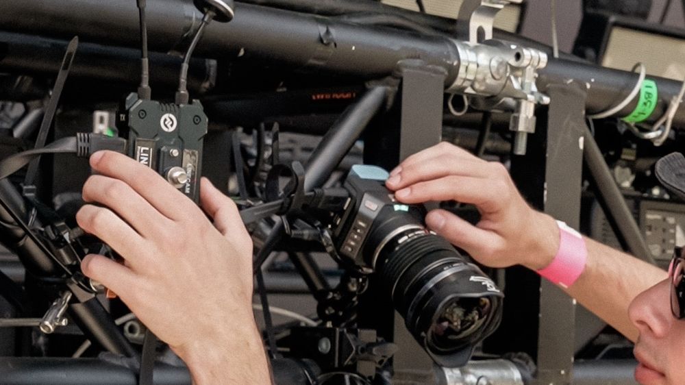 Técnico instalando una cámara compacta de estudio 4K con transmisor inalámbrico Hollyland en el truss del escenario
