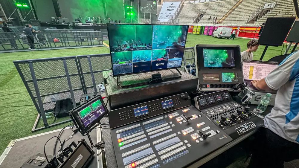 Puesto de realización con panel de mezcla ATEM y multiviewer frente al escenario de un concierto en una plaza de toros