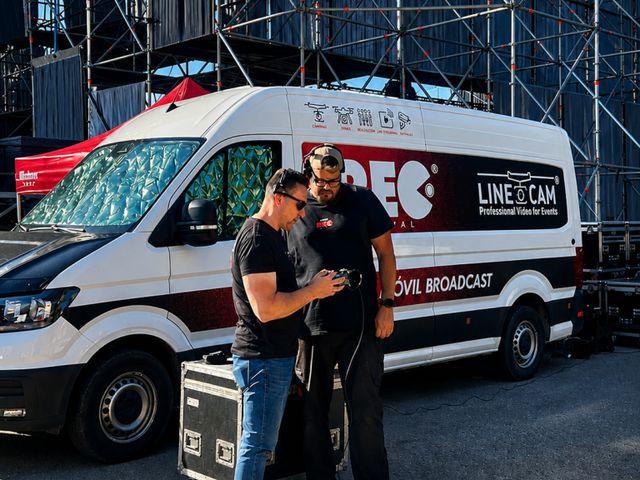 Unidad móvil broadcast y equipo técnico revisando la señal junto al escenario de un festival